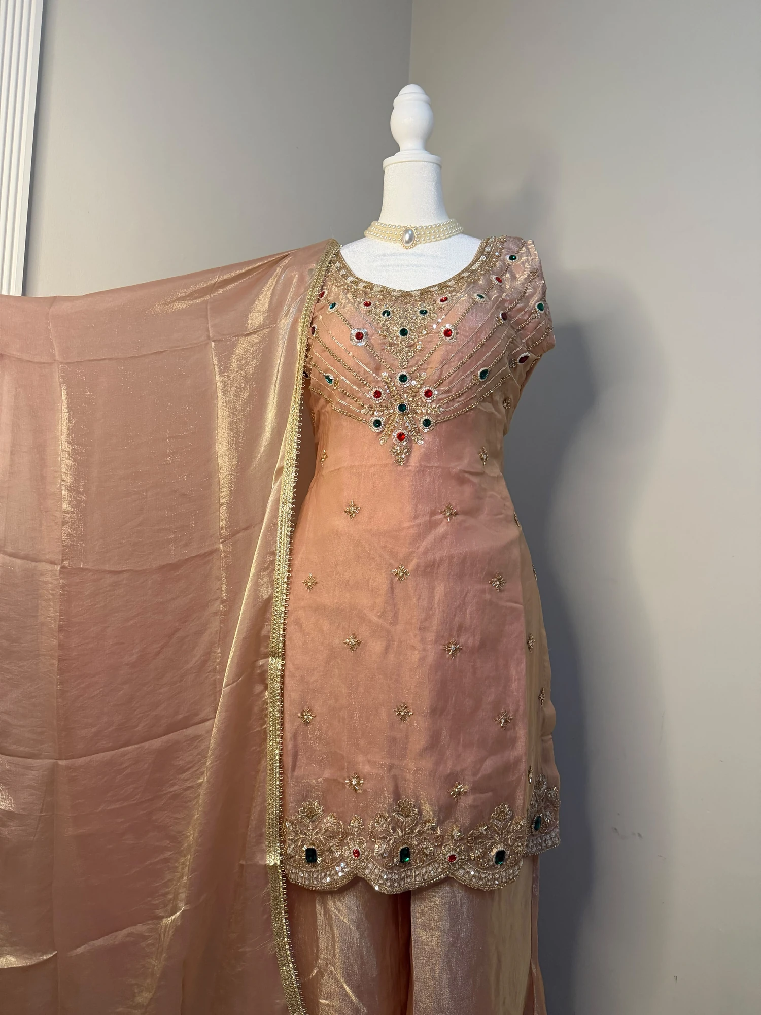 Front view of the peach/champagne embellished kurta outfit and drape