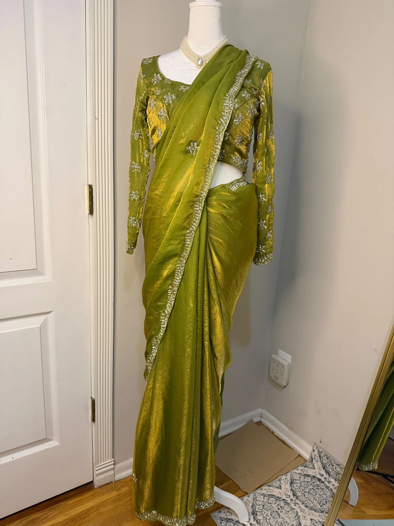 Full-length view of the olive-green saree with an embellished border and long-sleeved blouse